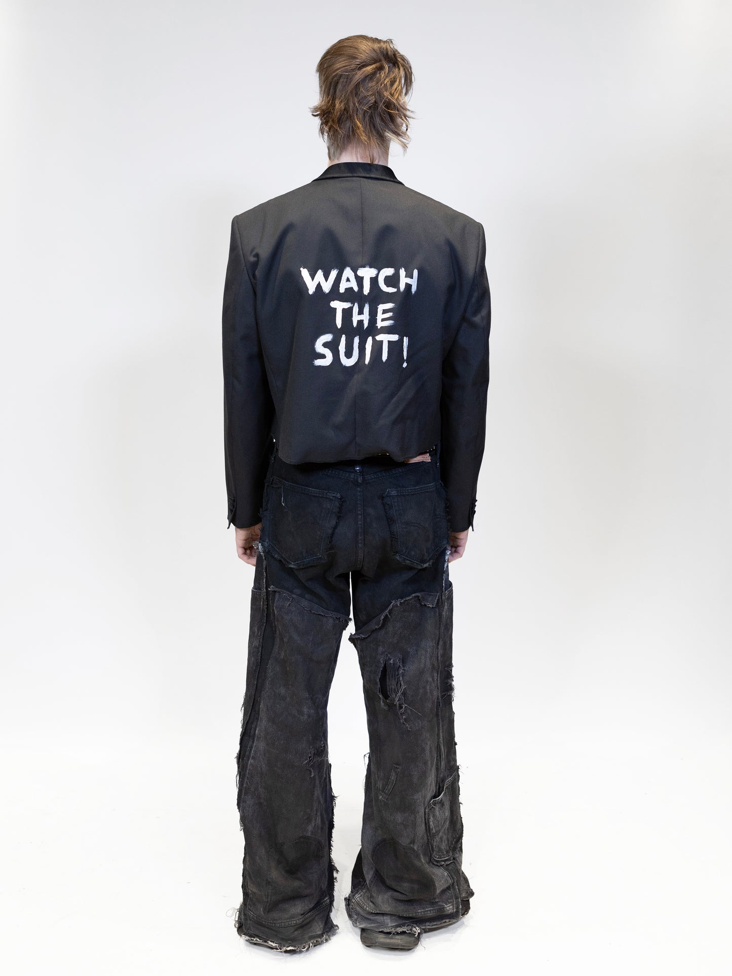 cropped black suit jacket on a model from the back shows model with jacket and jeans