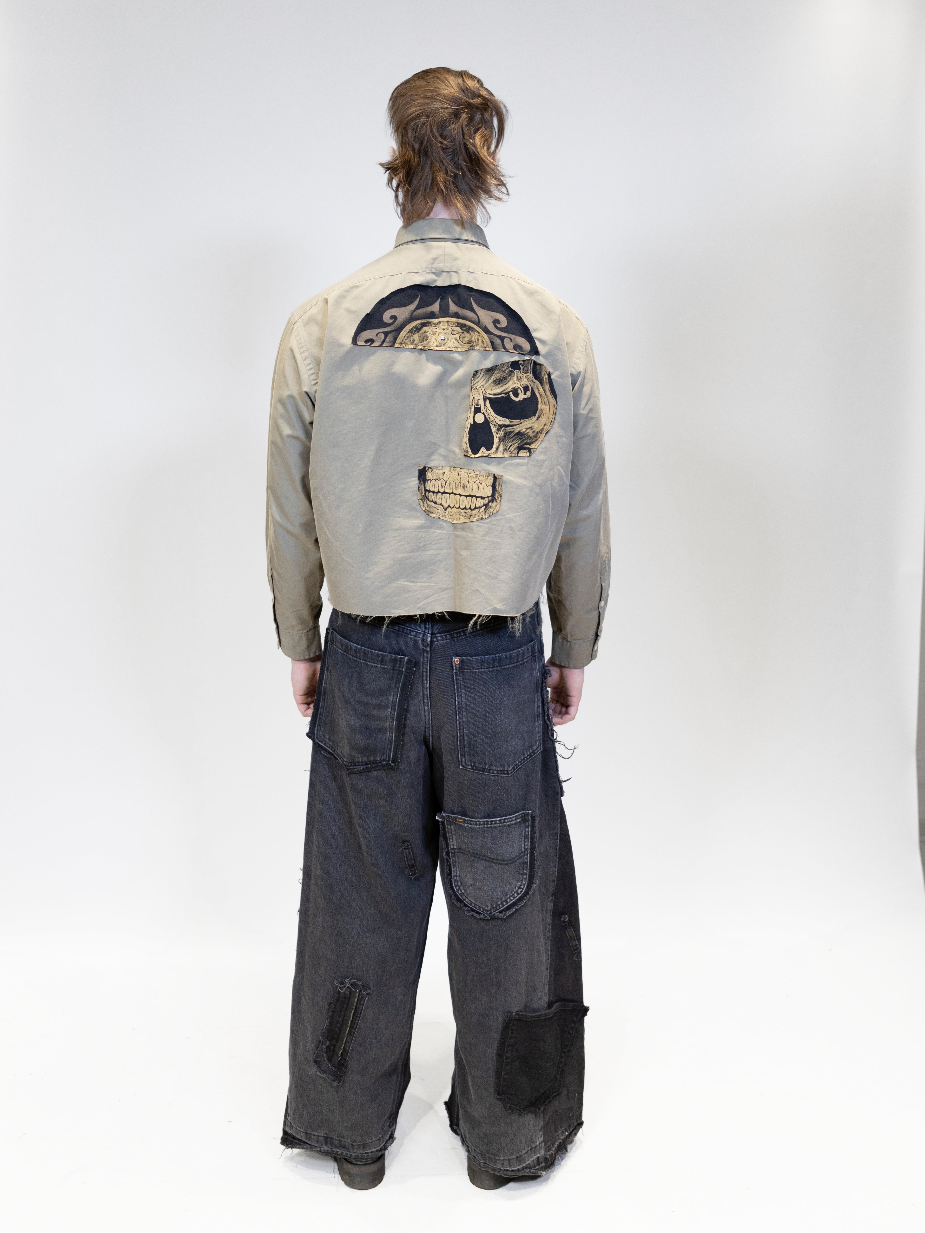 A male model wearing a tan shirt with patches, full body picture from backside