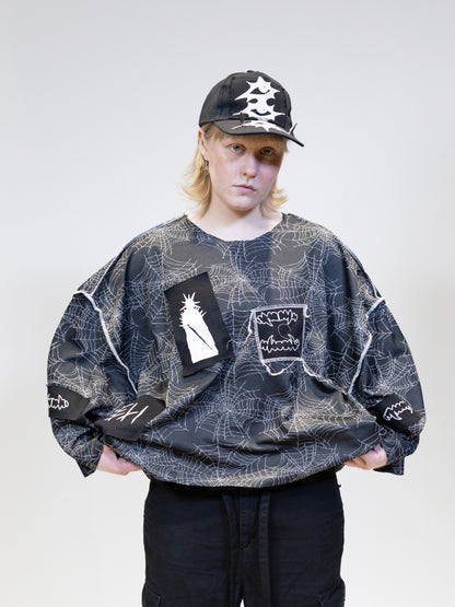 A model with Elieffekt cap and grey web shirt with patches